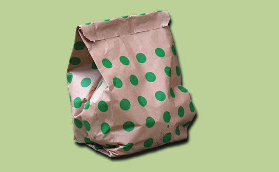 En brun papperspåse med gröna prickar på